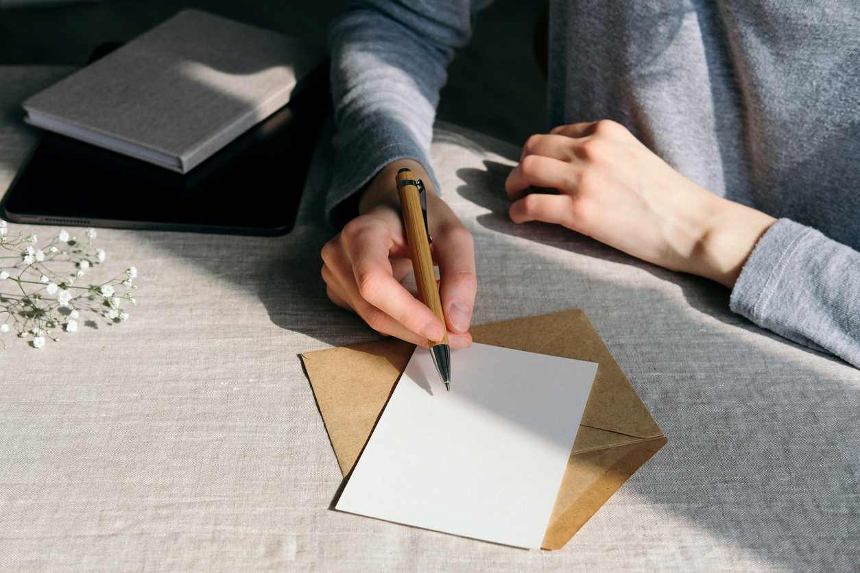 femme écrivant une lettre avec fleurs posées à coté