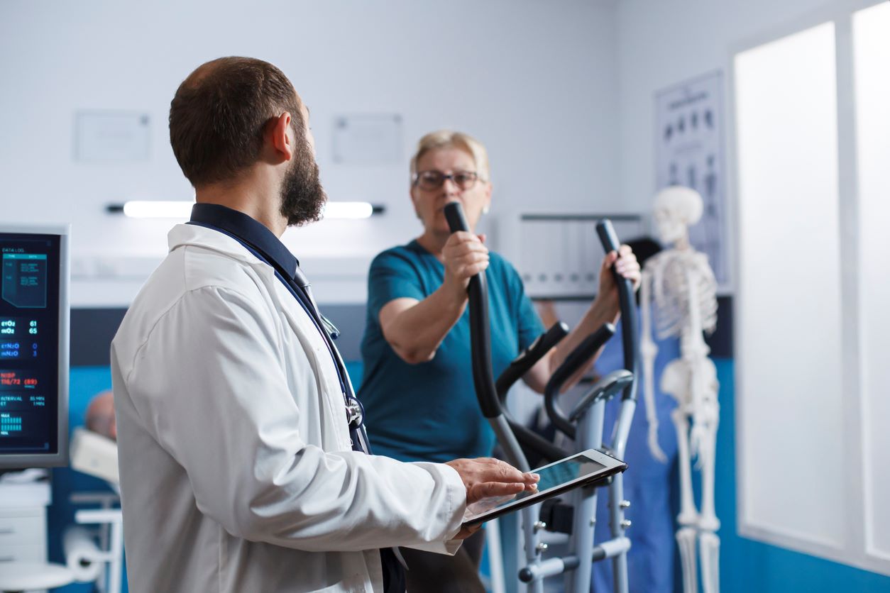 personne agée sur un vélo elliptique avec un medecin pour faire un test d'effort