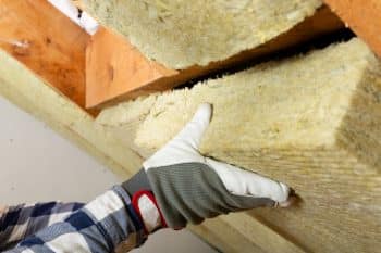 Man Installing Thermal Roof Insulation Layer Using Mineral Wool Panels. Attic Renovation And Insulation Concept