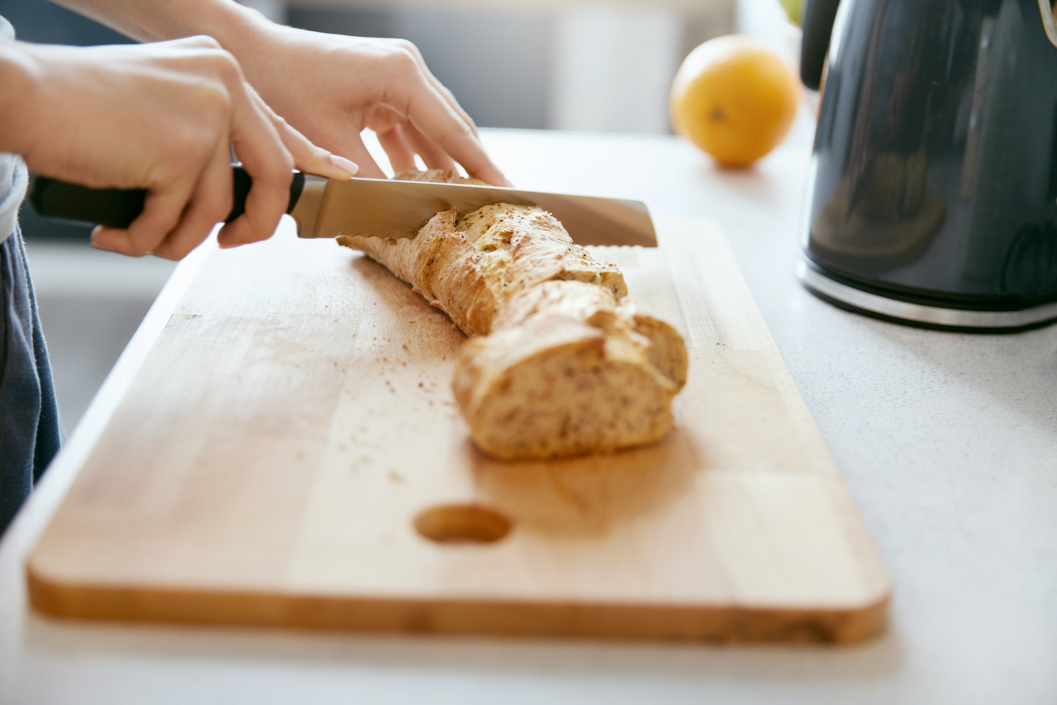 Woman Hands Cutting Bread In Kitchen.