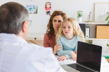 Young Adult Mother Visiting Pediatrician Doctor With Her Little Sick Daughter