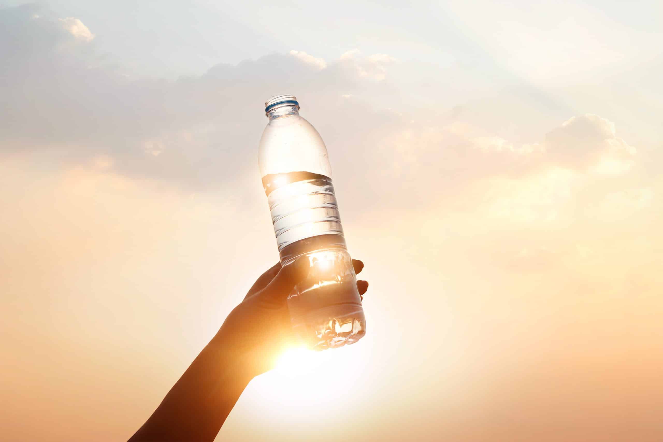 Hand Holding Drinking Water On Sunset Background