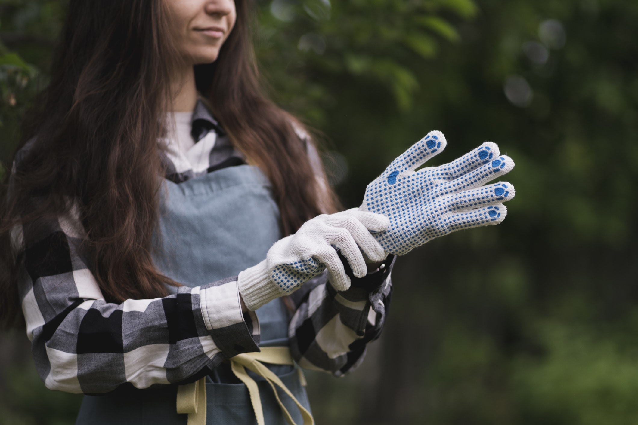 Young Woman Put On And Wear White Gloves In The Garden To Protect Hands