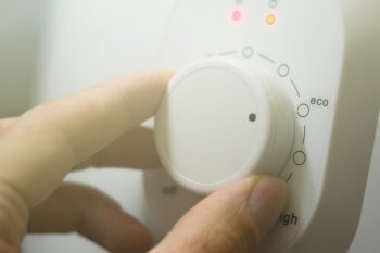 Setting The Temperature Controller Of The Heater In The Eco Mode Of Operation. Thermostat Of A Modern Heater. A Person Turns The Wheel Of The Temperature Controller With His Hand. Selective Focus