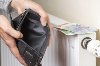 Woman Hand Places Euro Banknotes On Heating Radiator Battery And Looking To Empty Wallet. Expensive Heating Costs During Cold Season. Paying Bills