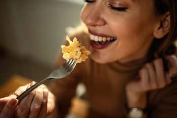 Close Up Of Happy Woman Enjoying While Eating Pasta.