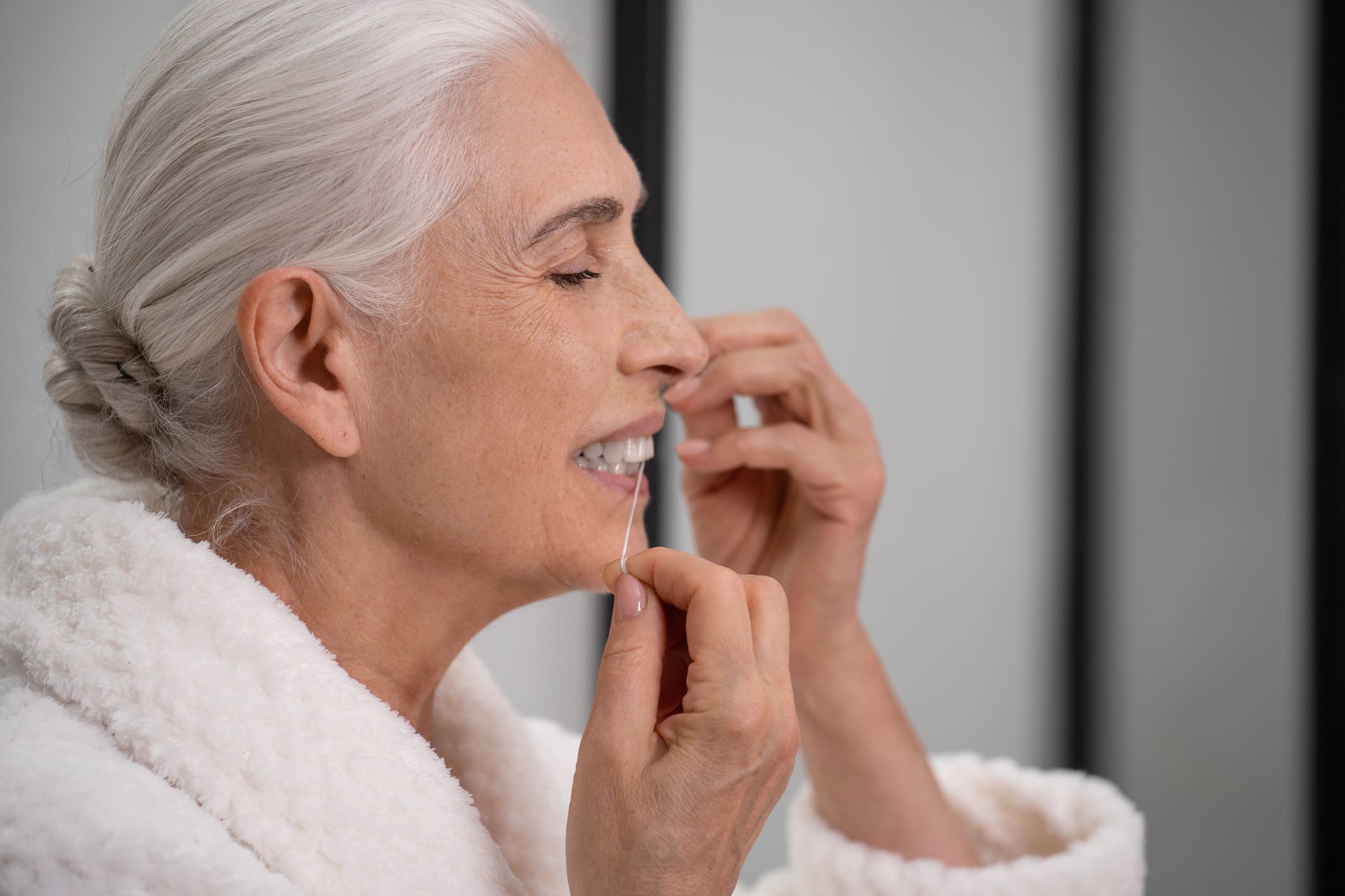 Aged Woman Cleaning Teeth With Dental Floss