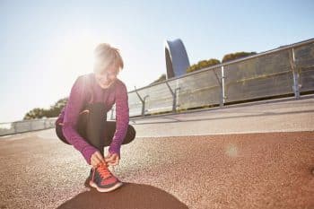 Get Ready. Full Length Shot Of Active Mature Woman Wearing Sportswear Tying Shoelaces On Sporty Sneakers While Getting Ready For Running Outdoors On A Sunny Day