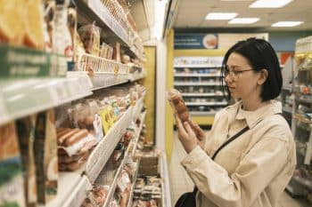 A Young Woman In A Grocery Supermarket Chooses Food. Shopping Concept