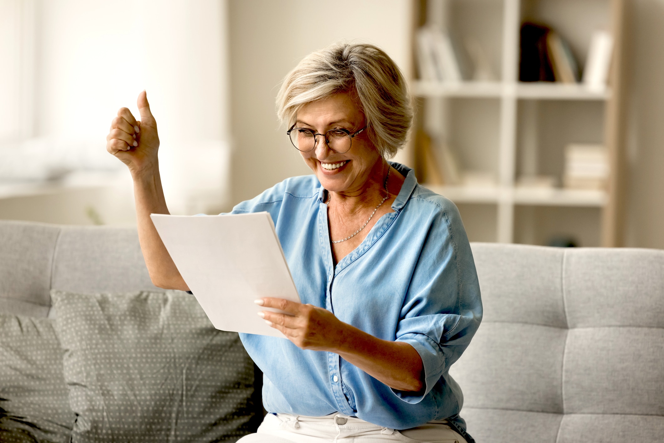 Cheerful Excited Older Woman In Glasses Reading Paper Document