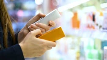A Female Customer Compares Two Skincare Product, Reading Labels With Ingredients