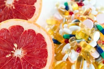 Pink Grapefruit And Pills, Vitamin Supplements On White Background